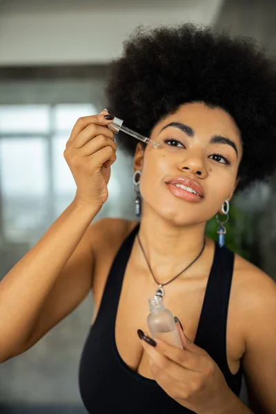 Genç Afrikalı Amerikalı Kadın Banyoda Yüzüne Kozmetik Serumu Sürüyor — Stok fotoğraf