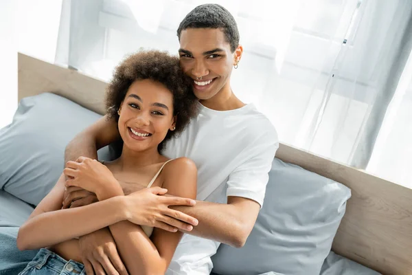 Young African American Man Piercing Embracing Happy Girlfriend Bedroom — Stock Photo, Image