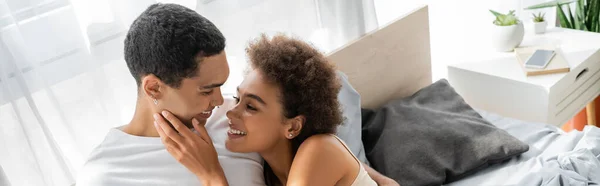 快乐的非洲女人在卧室里摸着快乐男朋友的脸 挂着横幅 — 图库照片