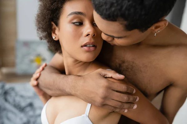 穿着女士内衣的性感的非洲女人看着情人在卧室里拥抱她 — 图库照片