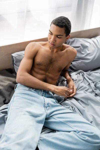 Ung Och Skjorta Afrikansk Amerikansk Man Sitter Grå Sängkläder Jeans — Stockfoto