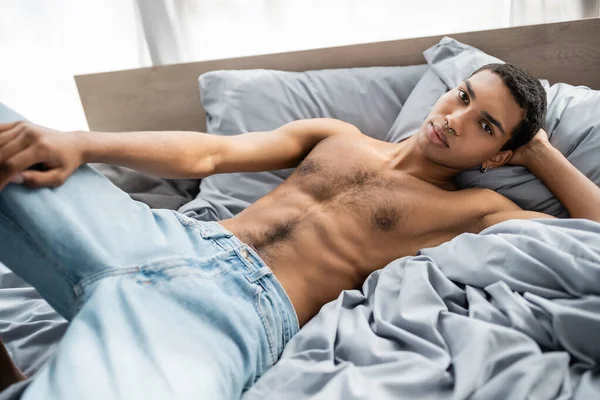 Muskulös Afrikansk Amerikansk Man Jeans Liggande Grå Sängkläder Banderoll — Stockfoto