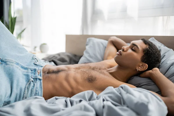 Shirtless African American Man Jeans Sleeping Grey Bedding Hands Head — Stock Photo, Image