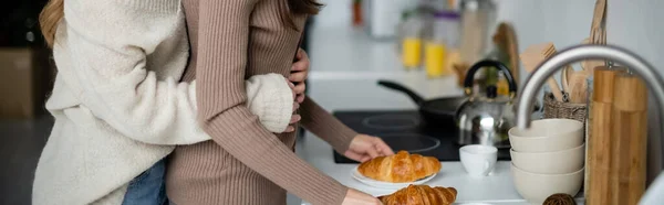 Vista Recortada Mujer Suéter Abrazando Novia Con Croissants Cocina Pancarta — Foto de Stock