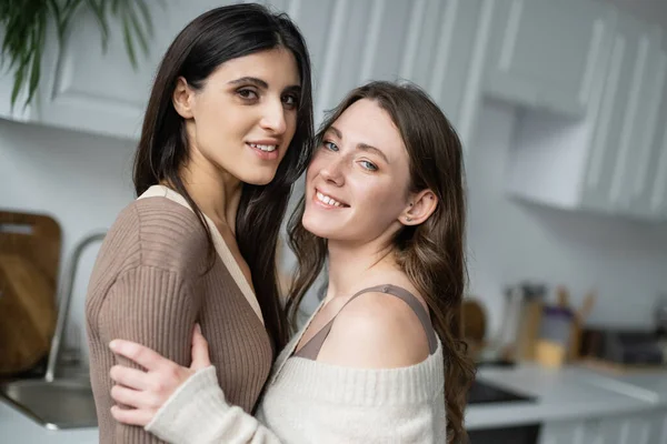 Sonriente Pareja Lesbianas Abrazando Mirando Cámara Casa — Foto de Stock
