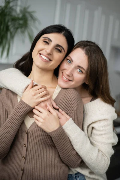 Šťastné Lesbičky Žena Objímající Přítelkyni Při Pohledu Kameru Doma — Stock fotografie