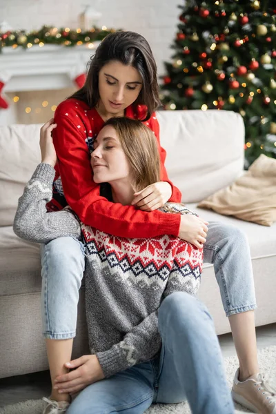 Mujer Joven Suéter Abrazando Novia Durante Celebración Navidad Casa — Foto de Stock