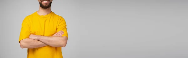 身穿黄色T恤 满脸笑容的男人站在灰色横幅上交叉着双臂的剪影 — 图库照片