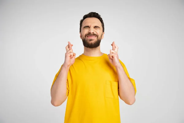 Worried Man Yellow Shirt Standing Closed Eyes Crossed Fingers Isolated — Stock Photo, Image