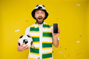 Çizgili eşarplı, futbol topu ve sarı ekranlı akıllı telefonlu hayret verici bir spor hayranıyım. 