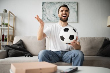 KYIV, UKRAINE - 21 Ekim 2022: hoşnutsuz adam futbol tutuyor ve evinde şampiyonluk seyrediyor