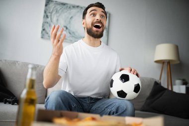 KYIV, UKRAINE - 21 Ekim 2022: Futbol oynayan ve evinde şampiyonayı izlerken el kol hareketi yapan neşeli adam