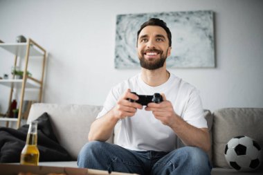 KYIV, UKRAINE - 21 Ekim 2022: evde joystick tutarken video oyunu oynayan mutlu adam