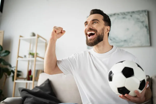 Křičící Vousatý Muž Držící Fotbalový Míč Ukazující Vítězství Gesto Při — Stock fotografie