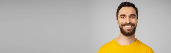 穿着鲜艳的黄色T恤的快乐胡子男子的肖像 看着被灰色横幅隔开的相机 — 图库照片