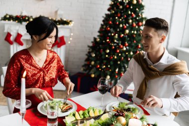 Hamile Asyalı kadın romantik bir Noel yemeğinde mutlu kocaya gülümsüyor. 