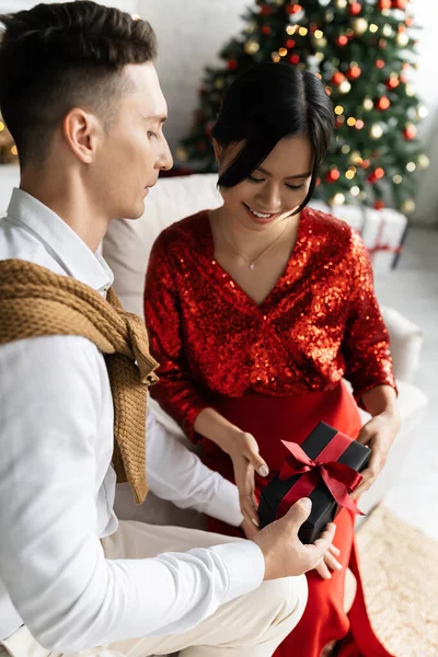 Young Husband Gifting Christmas Present Pregnant Asian Wife Sofa Home — Stock Photo, Image