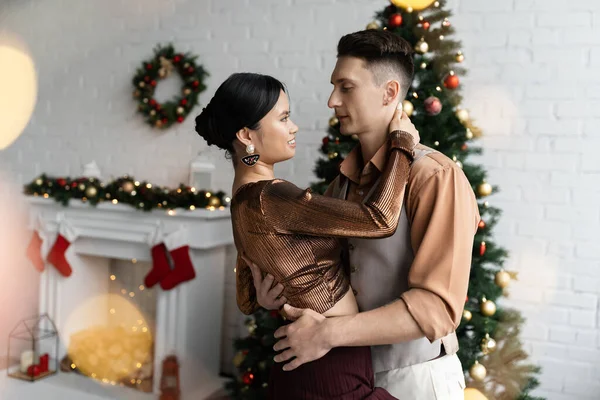 Young Interracial Couple Festive Outfits Hugging Christmas Tree — Stock Photo, Image
