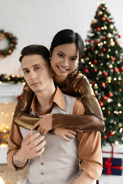 Fröhliche Asiatische Frau Umarmt Mann Neben Geschmücktem Weihnachtsbaum — Stockfoto