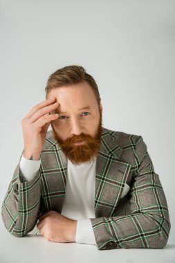 Gri renkli kameraya bakan ceketli şık bir adamın portresi. 