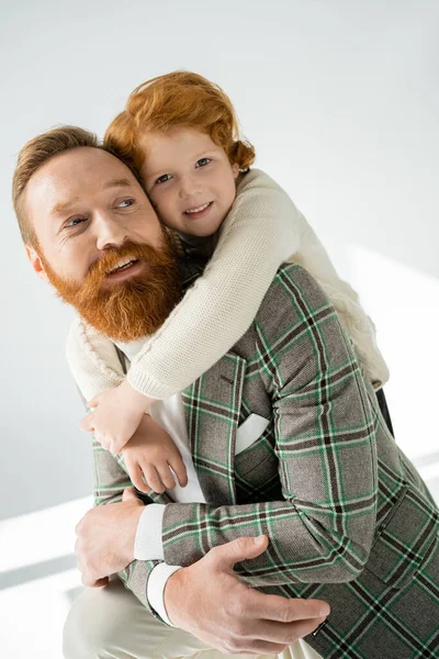 Sonriente Pelirrojo Niño Abrazando Elegante Padre Sobre Fondo Gris Con —  Fotos de Stock