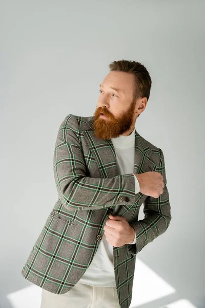 Модний Бородатий Чоловік Регулює Куртку Сірому Фоні Сонячним Світлом — стокове фото