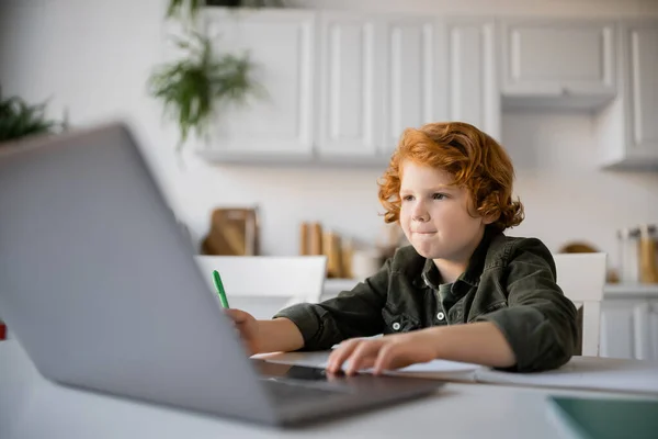 Koncentrált Vörös Hajú Fiú Laptoppal Miközben Otthon Tanul Konyhában — Stock Fotó