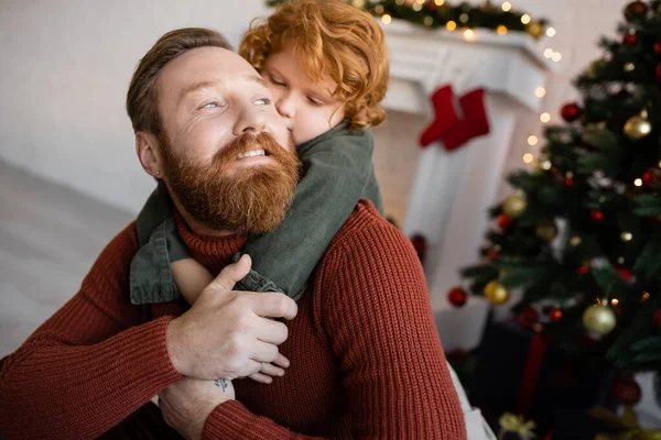 Pelirroja Niño Abrazando Feliz Barbudo Papá Mientras Celebrando Navidad Casa — Foto de Stock