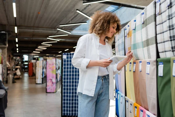 Cheerful Saleswoman Holding Digital Tablet While Checking Plaid Fabric Textile — Stock Photo, Image