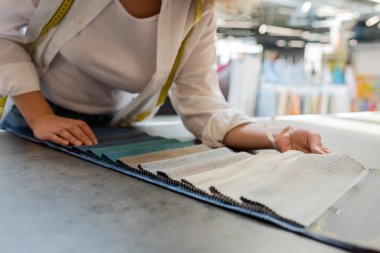 Mağazadaki tekstil örnekleri arasından seçim yapan genç satış elemanının kısmi görünümü