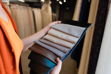 Tekstil dükkanında kumaş örnekleri tutan bulanık müşteri görüntüsü 