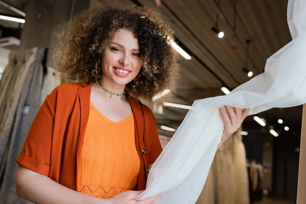 Позитивная Женщина Трогает Занавески Смотрит Камеру Текстильном Магазине — стоковое фото