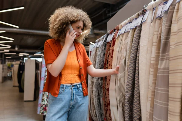 Kudrnatý Zákazník Mluví Smartphone Výběru Látky Textilním Obchodě — Stock fotografie