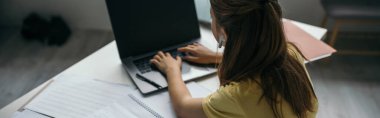 back view of girl typing on laptop with blank screen while studying at home, banner clipart