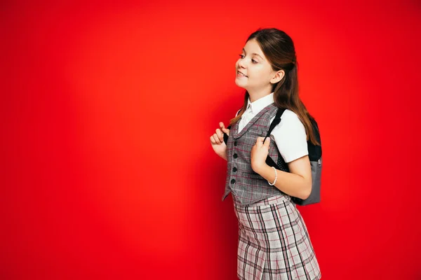 Glückliches Schulmädchen Mit Rucksack Das Isoliert Auf Rotem Banner Wegschaut — Stockfoto