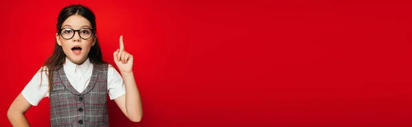 Возбужденный Ребенок Очках Указывая Вверх Пальцем Изолированы Красный Баннер — стоковое фото