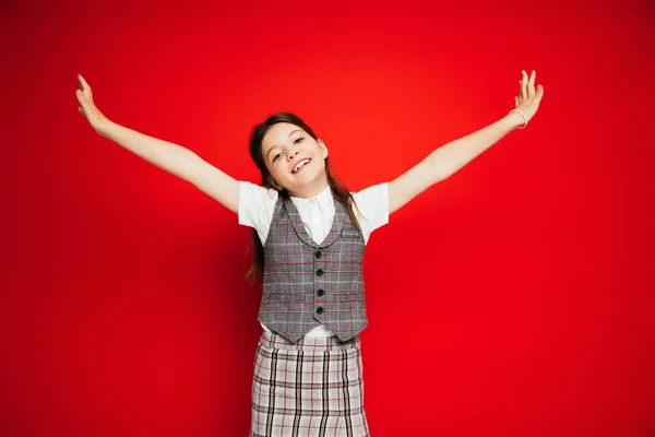 Veselá Dívka Stylovém Kostkovaném Oblečení Stojící Nataženýma Rukama Izolovanými Červené — Stock fotografie