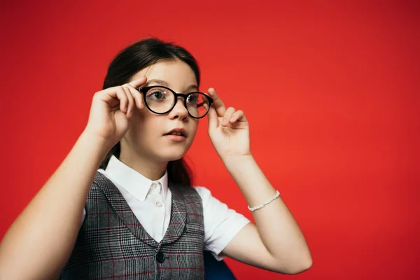 Dziewczyna Kamizelce Odwracając Wzrok Dostosowując Okulary Izolowane Czerwono — Zdjęcie stockowe