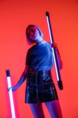 Neon lambalı genç bir kadının mercan arka plandaki kameraya bakış açısı düşük.