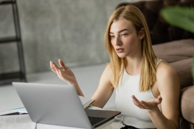 Blonde coach holding pen while having video call on laptop at home  clipart