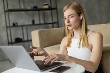 Coach in earphone having video call on laptop at home  clipart