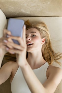Ağzını açmış, akıllı telefondan selfie çeken genç bir kadın. 