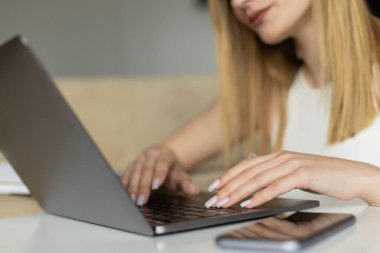 Evde boş ekran ile cep telefonunun yanında dizüstü bilgisayar kullanan bulanık koçun görüntüsü 
