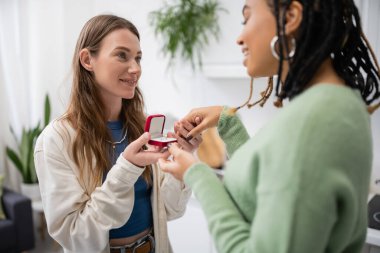 happy lesbian woman making proposal to african american girlfriend on valentines day clipart