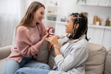 lesbian woman making proposal to happy african american girlfriend on valentines day clipart