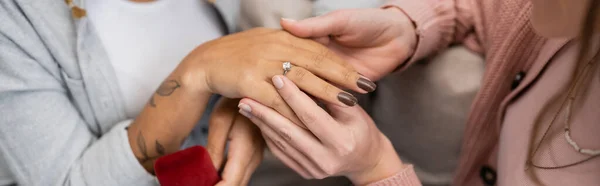 stock image cropped view of lesbian woman wearing engagement ring on finger of african american girlfriend, banner