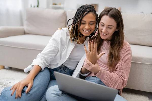 stock image lesbian african american woman smiling while showing engagement ring near girlfriend during video call 