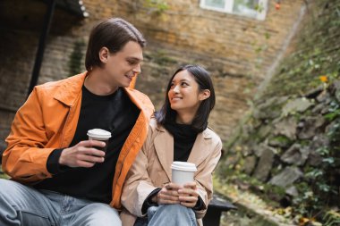 Gülümseyen ırklar arası bir çift kahve alıp kafenin terasında birbirlerine bakıyorlar. 