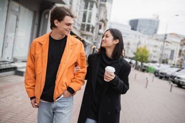 Kağıt bardakla gülen, etnik çeşitlilikte bir çift. 