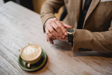 Kapuçino fincanının yanında bir adamın kol saatine dokunuşunu latte sanatıyla seyrelttim. 